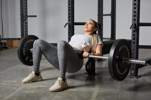A woman performs a barbell hip thrust.