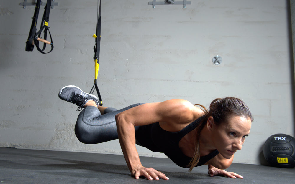 Action shot: Athlete performing push ups utilizing the TRX® CLUB4