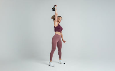 The REP Fitness Women's Rhea Cropped Tank Top in Wine front, kettlebell overhead