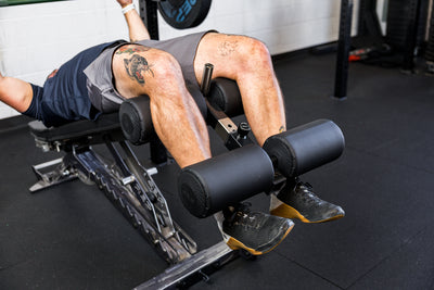 Athlete using the Adjustable Bench Leg Roller Attachment 2.0 for decline bench press