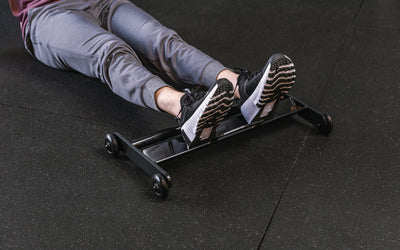 feet resting on the foot tray of the glute ham roller