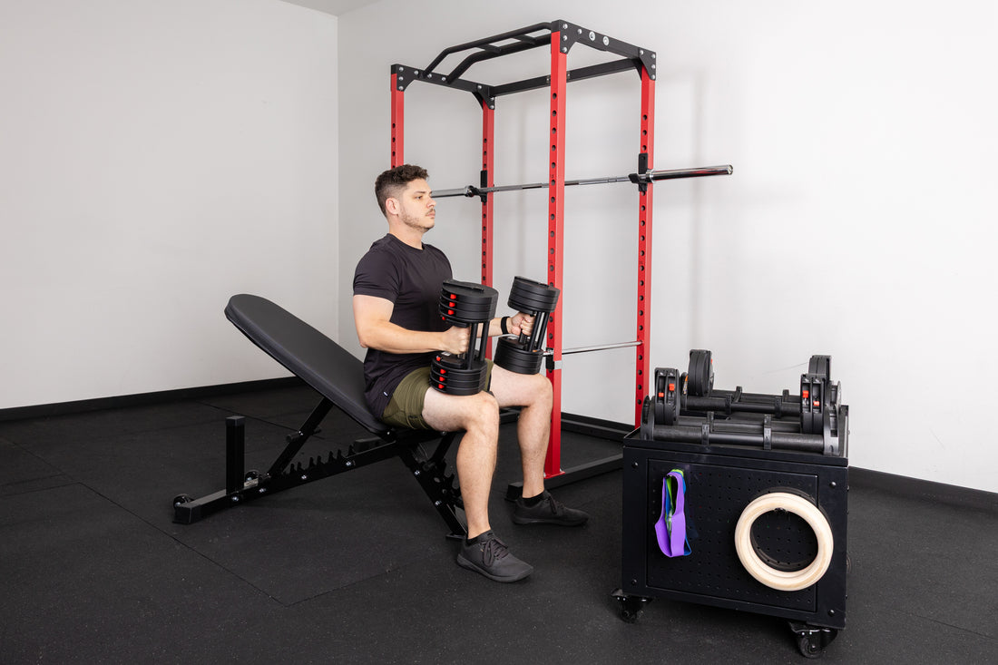An athlete preparing to incline bench press on the AB-3100 adjustable bench with the QuickDraw adjustable dumbbells