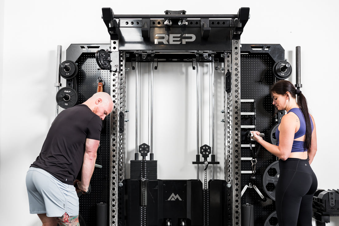 Two people doing exercises on a wall-mounted gym rack with Logo Plate Crossmember 2.0 Standard branded 'REP' on a white background.