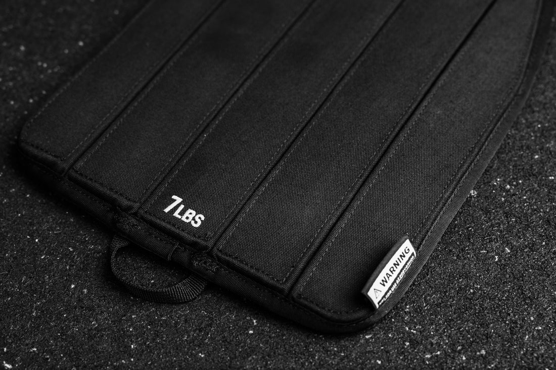 Black soft weight vest plate with '7 LBS' and branding on a dark surface