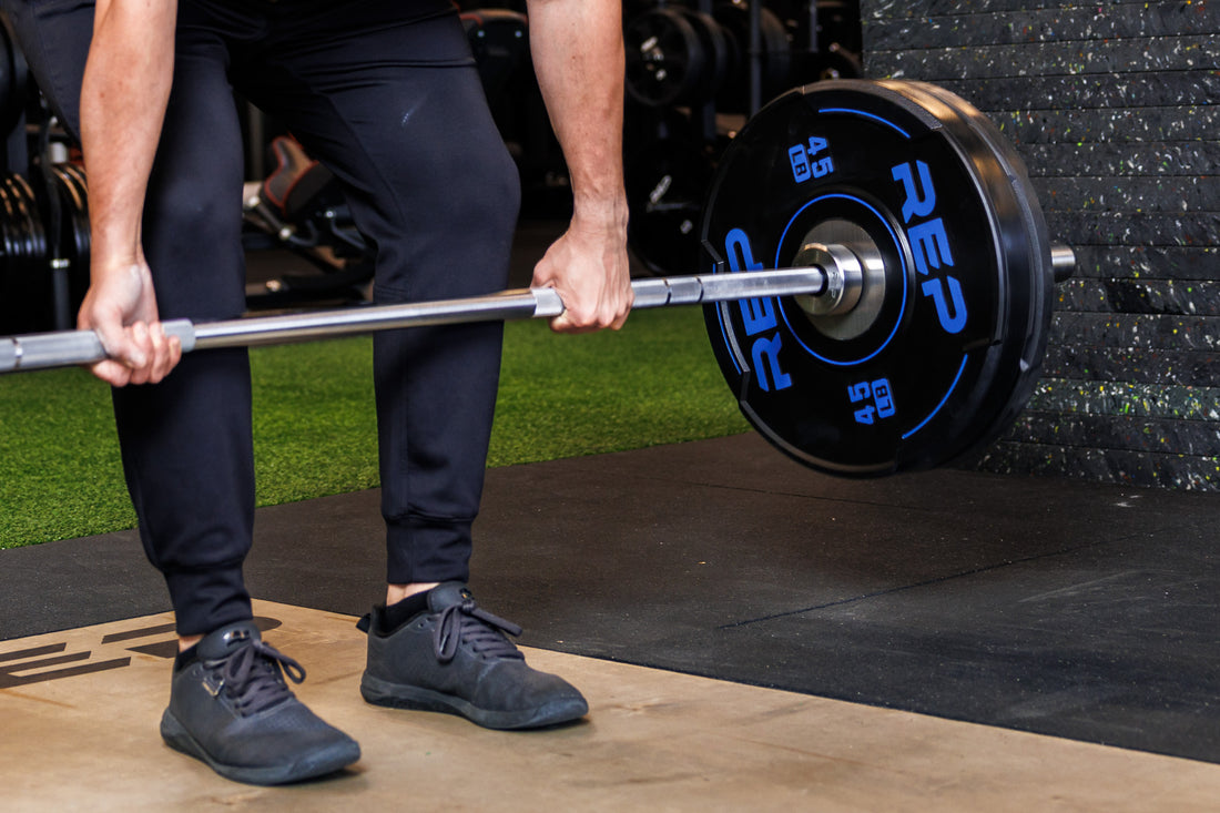 Close-up: Athlete lifts a barbell loaded with 45 lb and 25 lb REP Sport Bumper Plates 2.0 interlocked on the sleeve