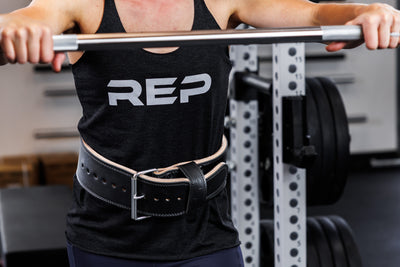 Front-shot: Athlete wearing the black REP Leather Lifting Belt approaching a barbell at shoulder height in a PR-5000 rack