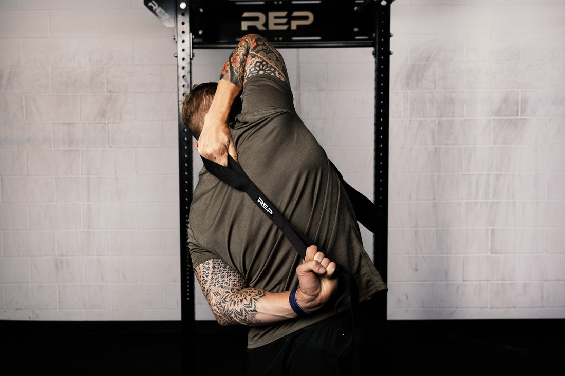 Person using a stretching band with 'REP' branding for should mobility in a gym setting.