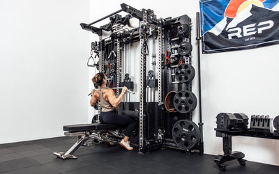 An athlete performing a lat pulldown on the Wall-Mounted Ares™ 2.0 while seated on a REP BlackWing™ bench